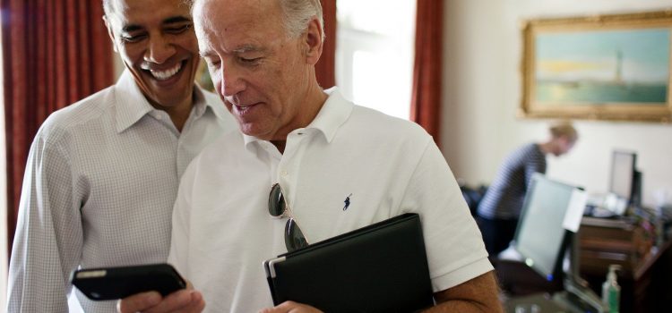 Photo of Joe Biden and Barack Obama looking at the screen of a phone being held by Biden