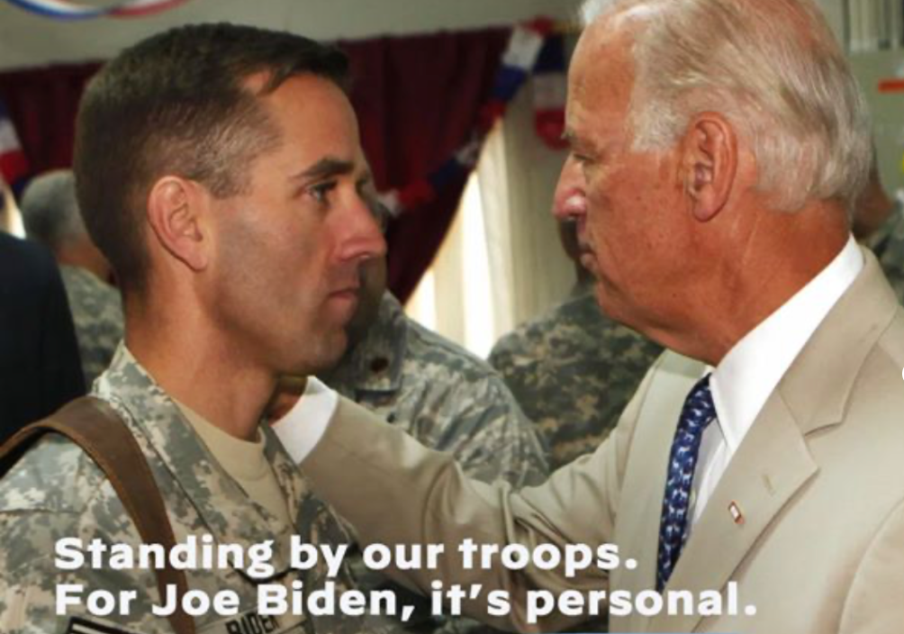 Body from Biden ad. The ad shows Biden affectionately placing his hand on his son Beau Biden. Beau Biden is dressed in military fatigues. The bottom of the image includes the following statement: "Standing by our troops. For Joe Biden, it's personal."