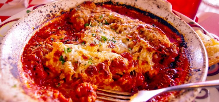Chicken parmesan served in a deep plate with a fork