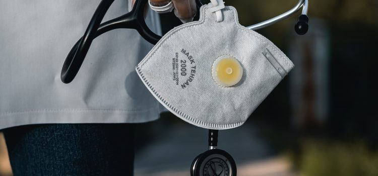 Photograph of a person's hand holding a stethoscope and a mask.